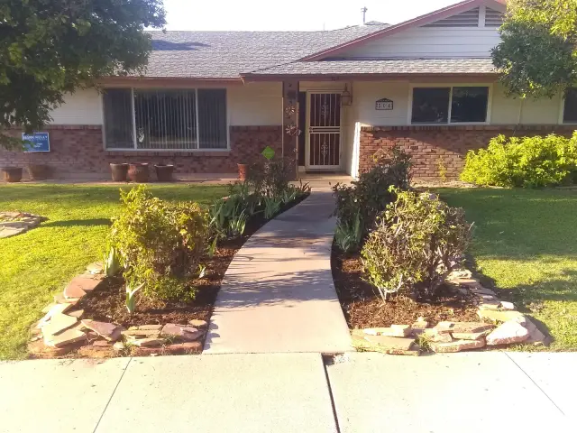 Front of a house with a clean walkway, stone-edged beds and cut lawn