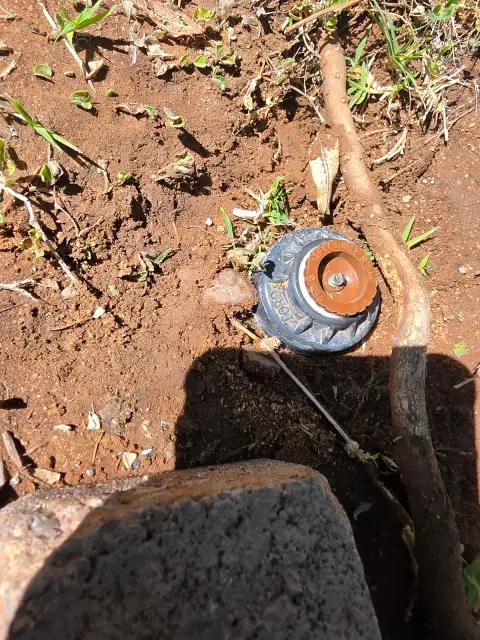 A rotor sprinkler body dug out of the ground mid-repair